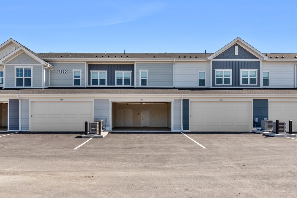 the front of a blue and white house with a garage door at Tivoli Green Apartments & Townhomes, Mount Pleasant, WI