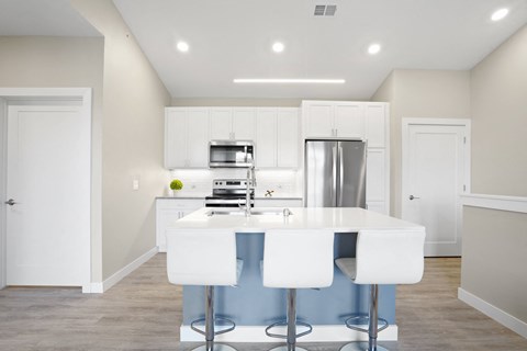 a kitchen with white cabinets and a white island with white chairs