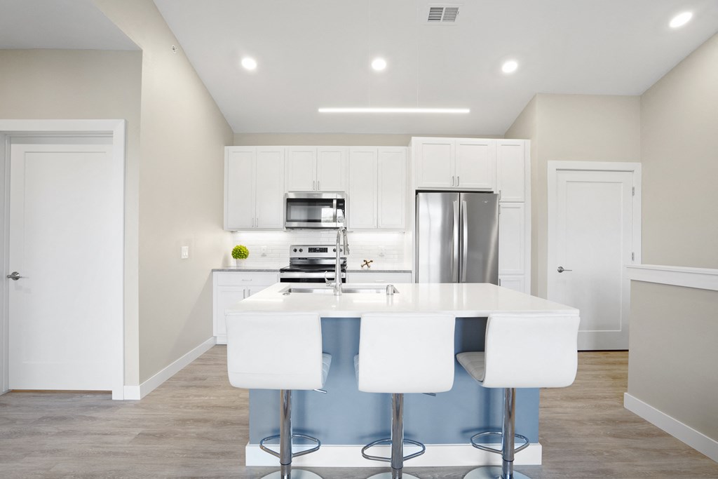 a kitchen with white cabinets and a white counter top and a stainless steel refrigerator