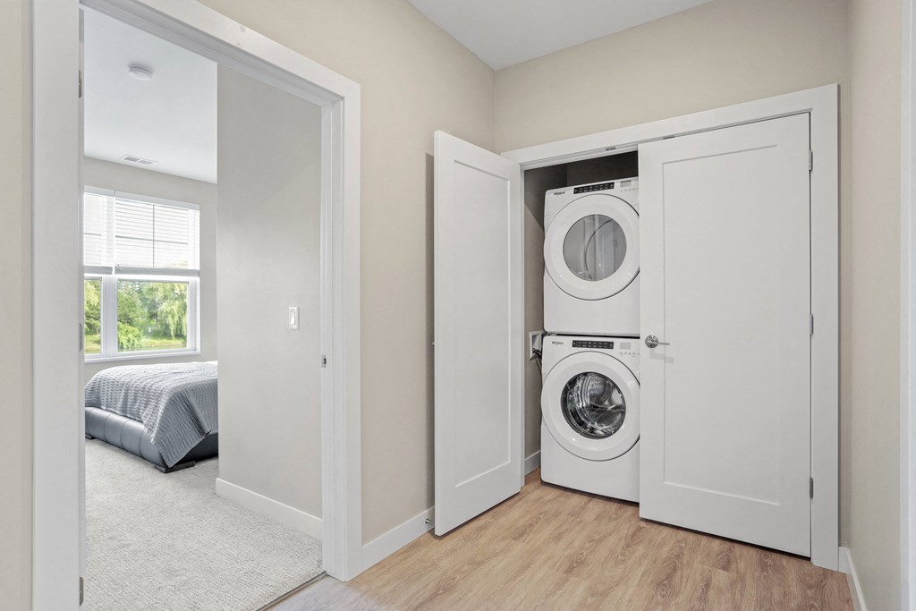 a white washer and dryer in a closet in a room with a bedroom