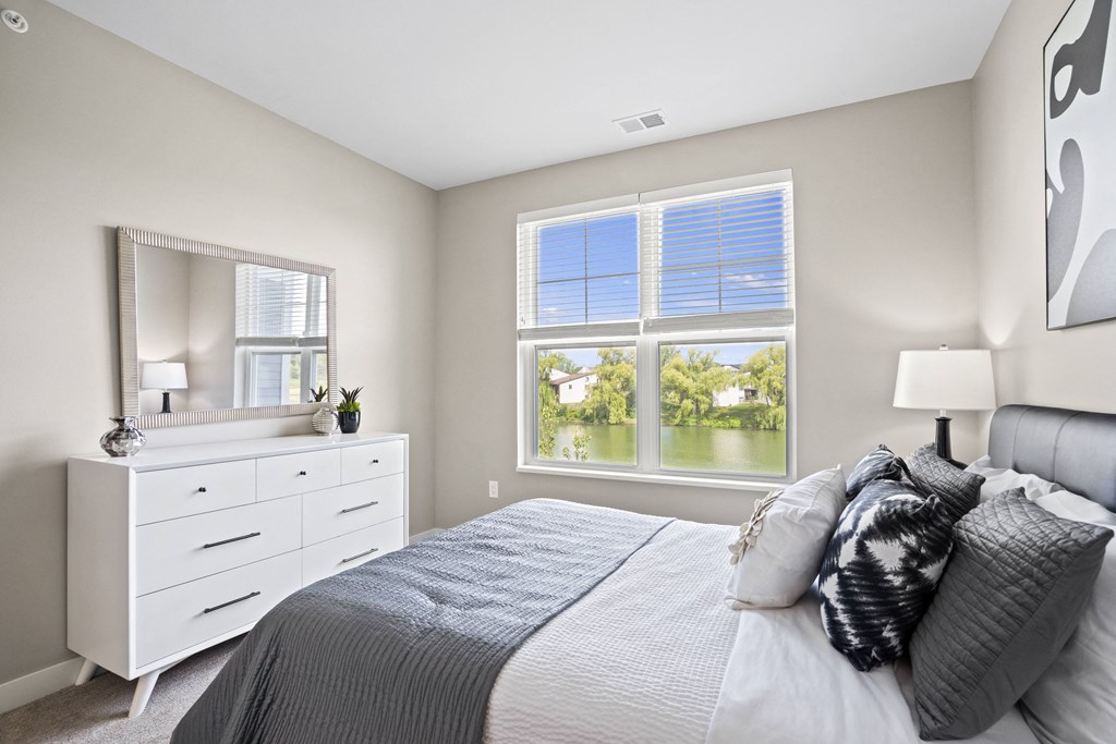 a bedroom with a large window and a bed with pillows
