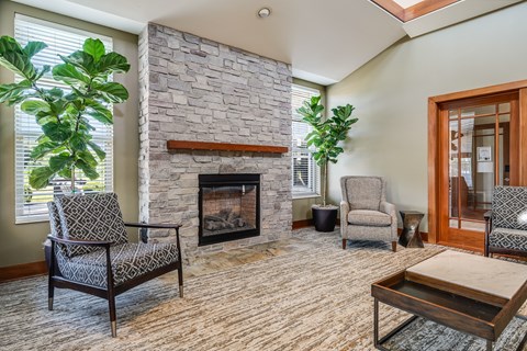 A living room with a stone fireplace and two chairs.