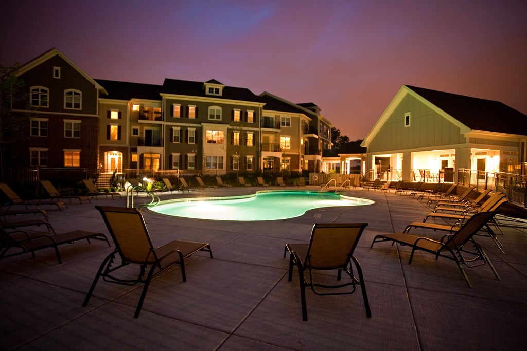 an empty pool at night with an apartment building in the background