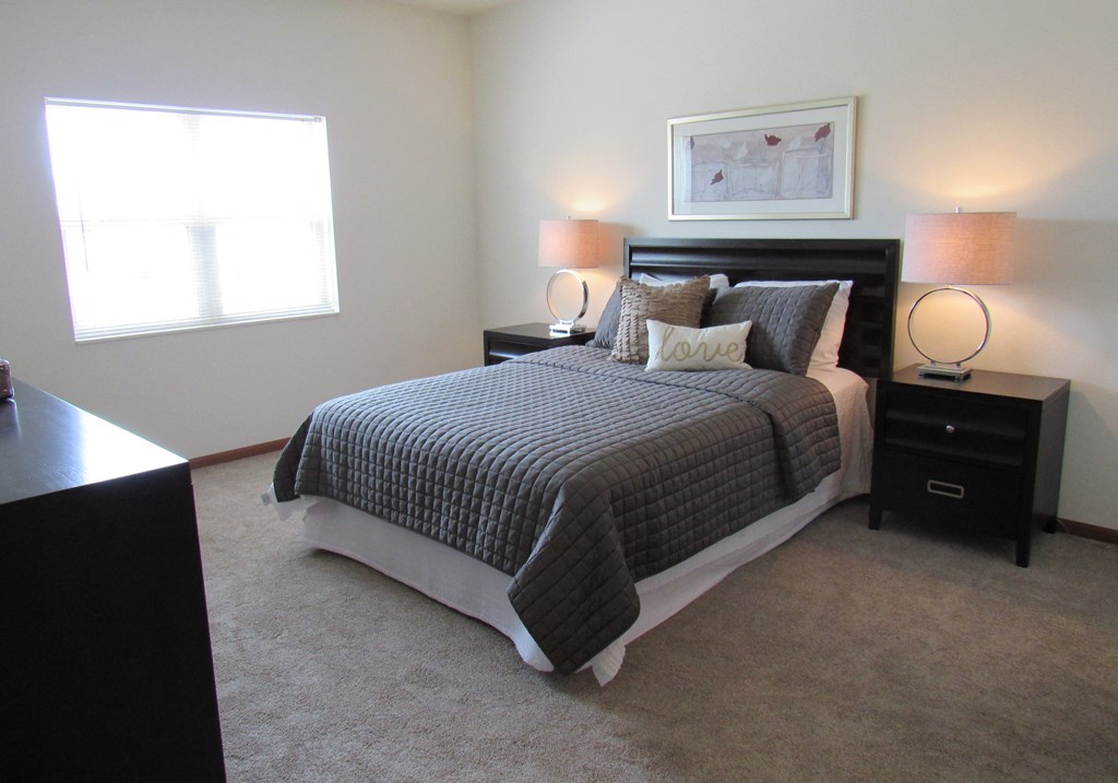 a bedroom with a bed and two night stands and a window