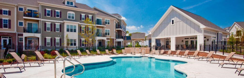 a swimming pool with chairs in front of an apartment building