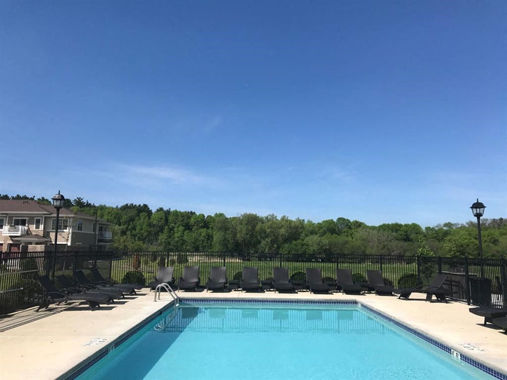 a swimming pool with black chairs around it