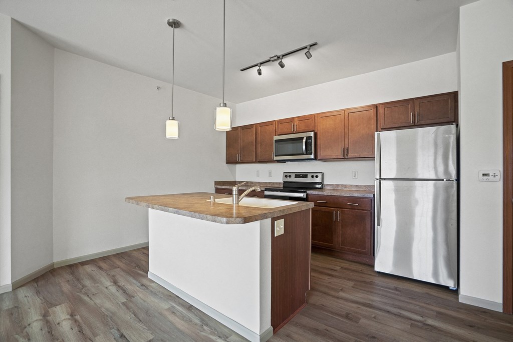 an empty kitchen with a white island and stainless steel refrigerator