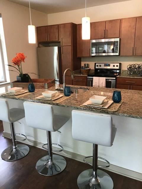 A kitchen with a granite countertop and white bar stools.