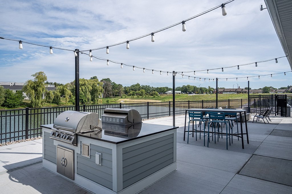 a patio with a grill and a table with chairs