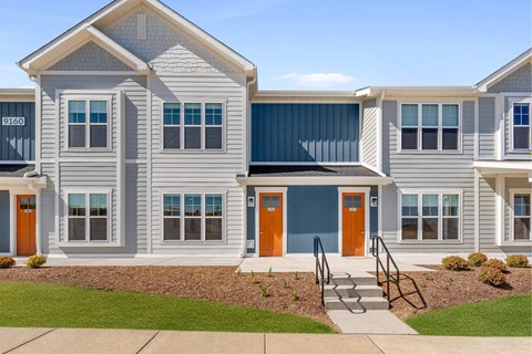 A modern two-story house with a grey exterior and a blue roof.