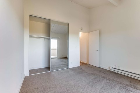 a bedroom with a carpeted floor and mirrors on the wall