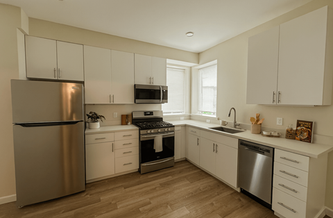 A kitchen with white cabinets and a stainless steel refrigerator.