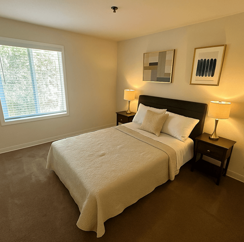 A bedroom with a large bed and two lamps.