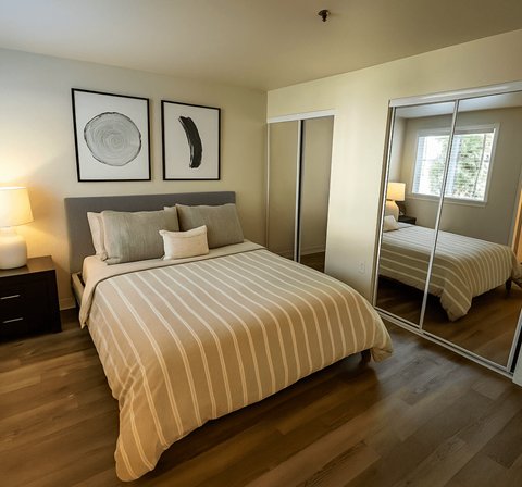 A bedroom with a large bed and a mirrored closet door.