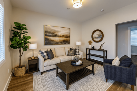 A living room with a large painting on the wall and a plant in a basket.