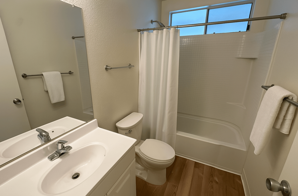A white bathroom with a toilet, sink, and shower.at Glenn Manor, Rohnert Park, CA 94928