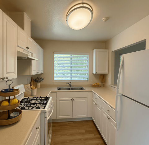 A kitchen with white cabinets and a white refrigerator.