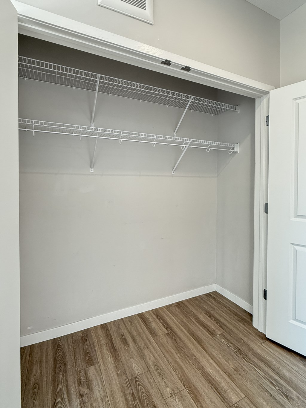 A white closet with a white door and shelves.
