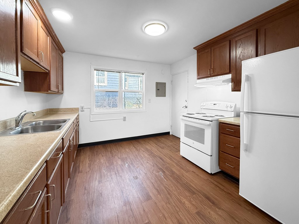 A kitchen with white appliances and wooden cabinets.