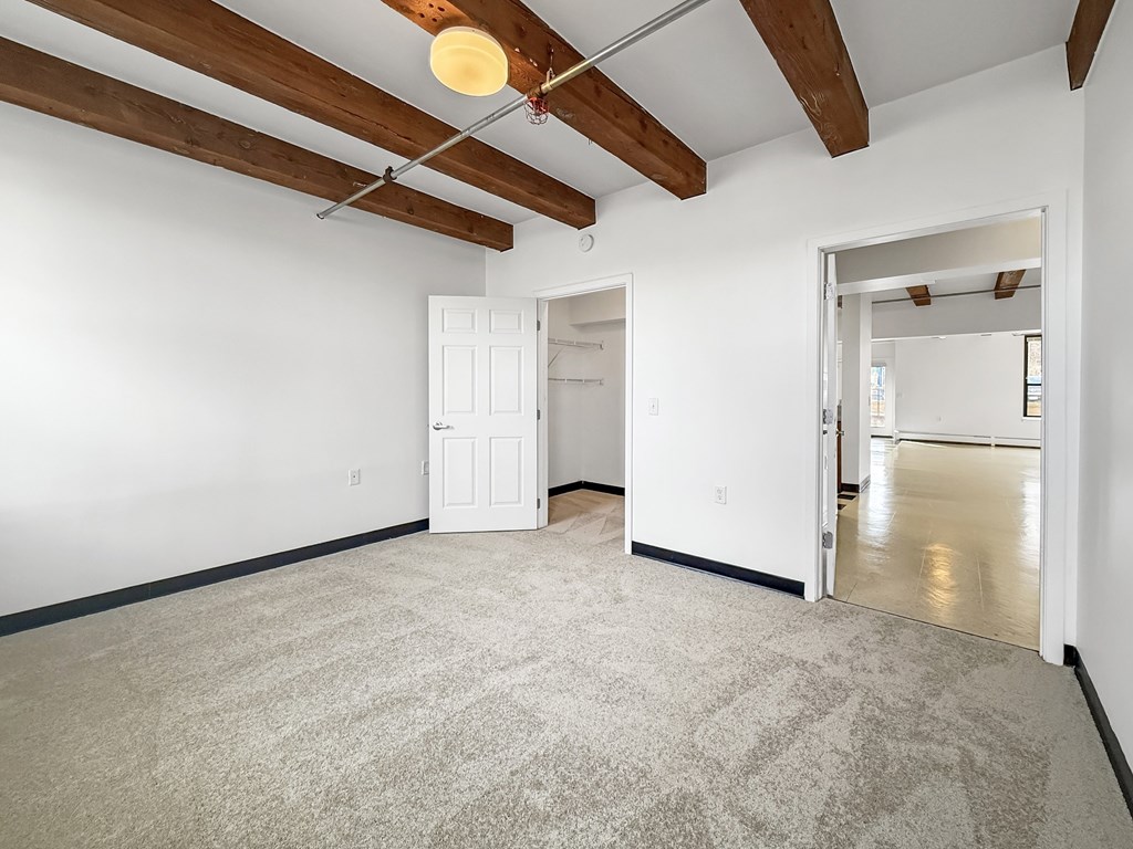 A room with a white door and a carpeted floor.