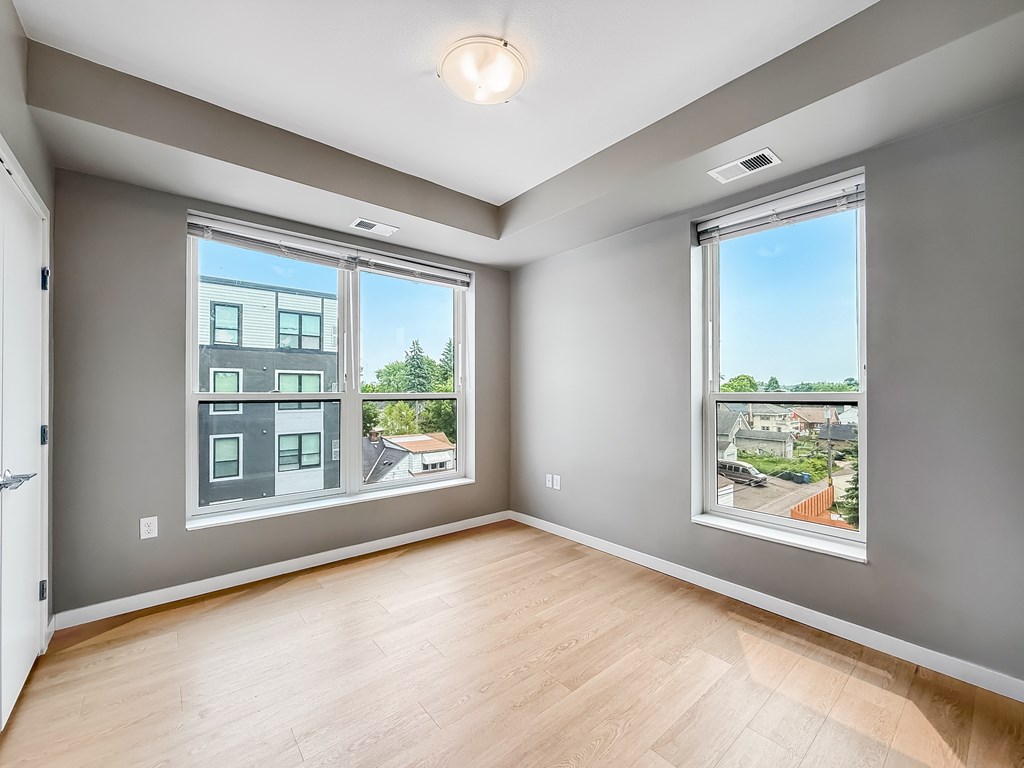 A room with a large window showing a view of a street and houses.