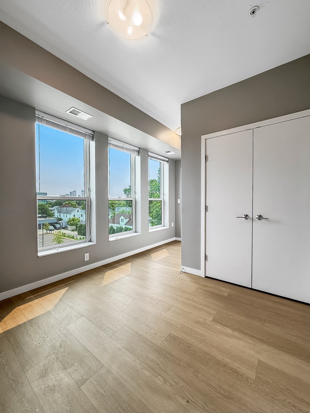 A room with a white door and a window overlooking a cityscape.