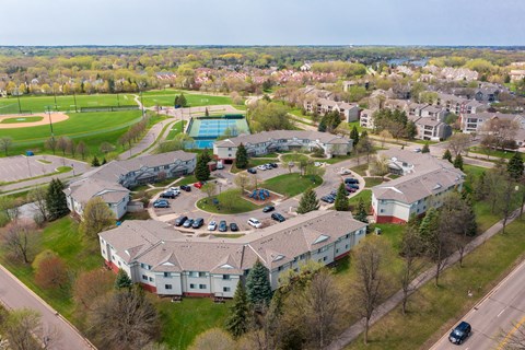 A bird's eye view of a residential area with a swimming pool and baseball field.
