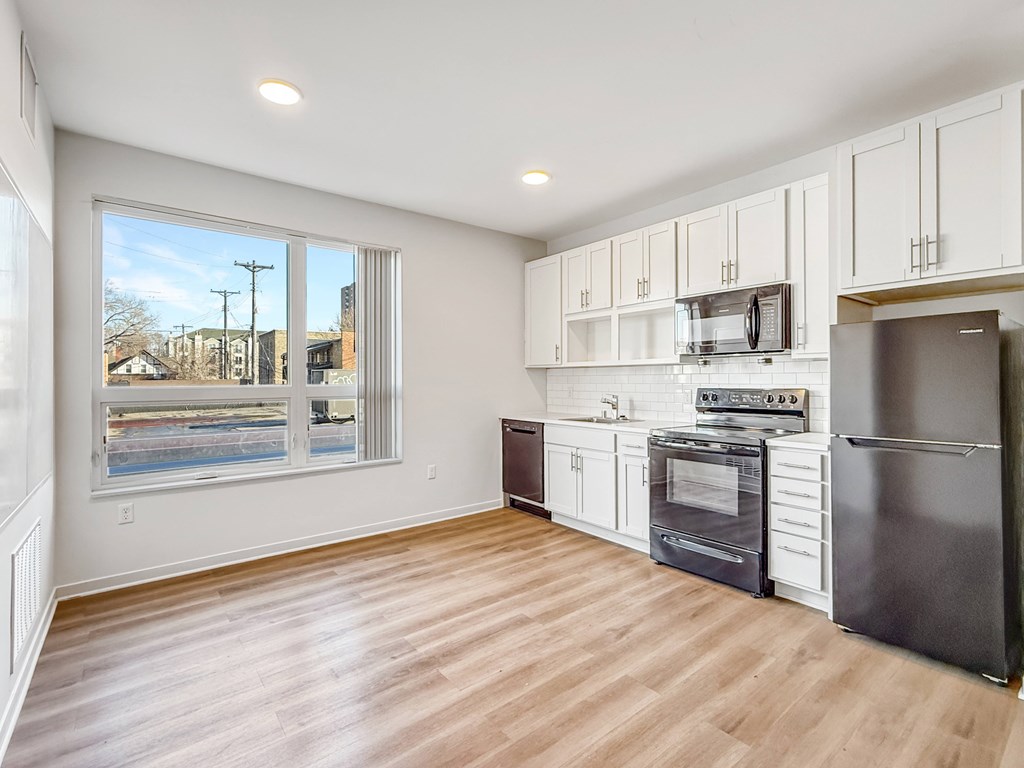 A kitchen with white cabinets and a black refrigerator.