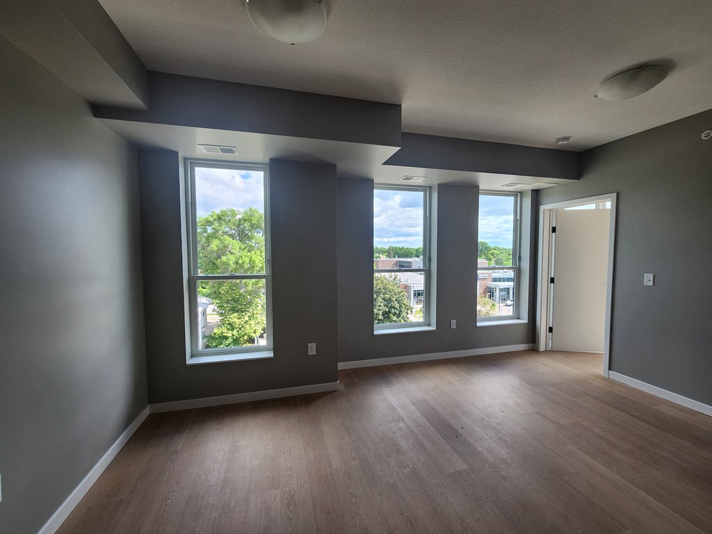 an empty living room with a wood floor and large windows