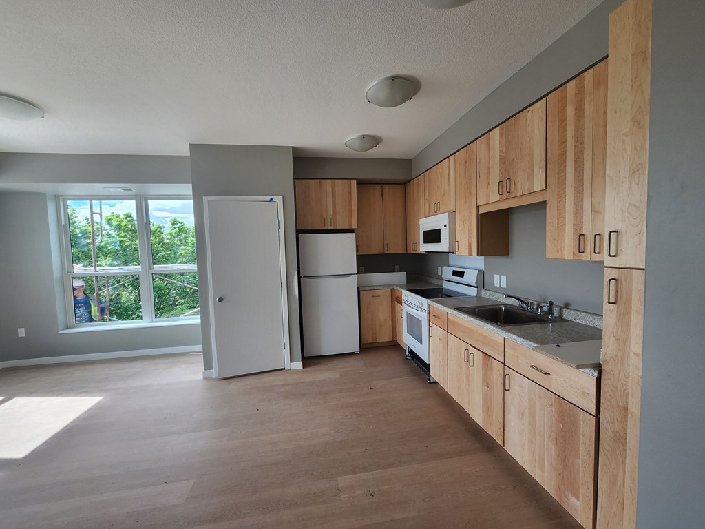 an empty kitchen with wooden cabinets and a white refrigerator