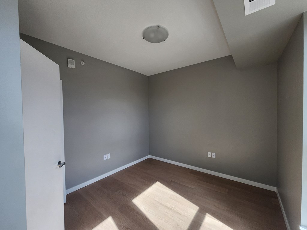 an empty room with wooden floors and grey walls
