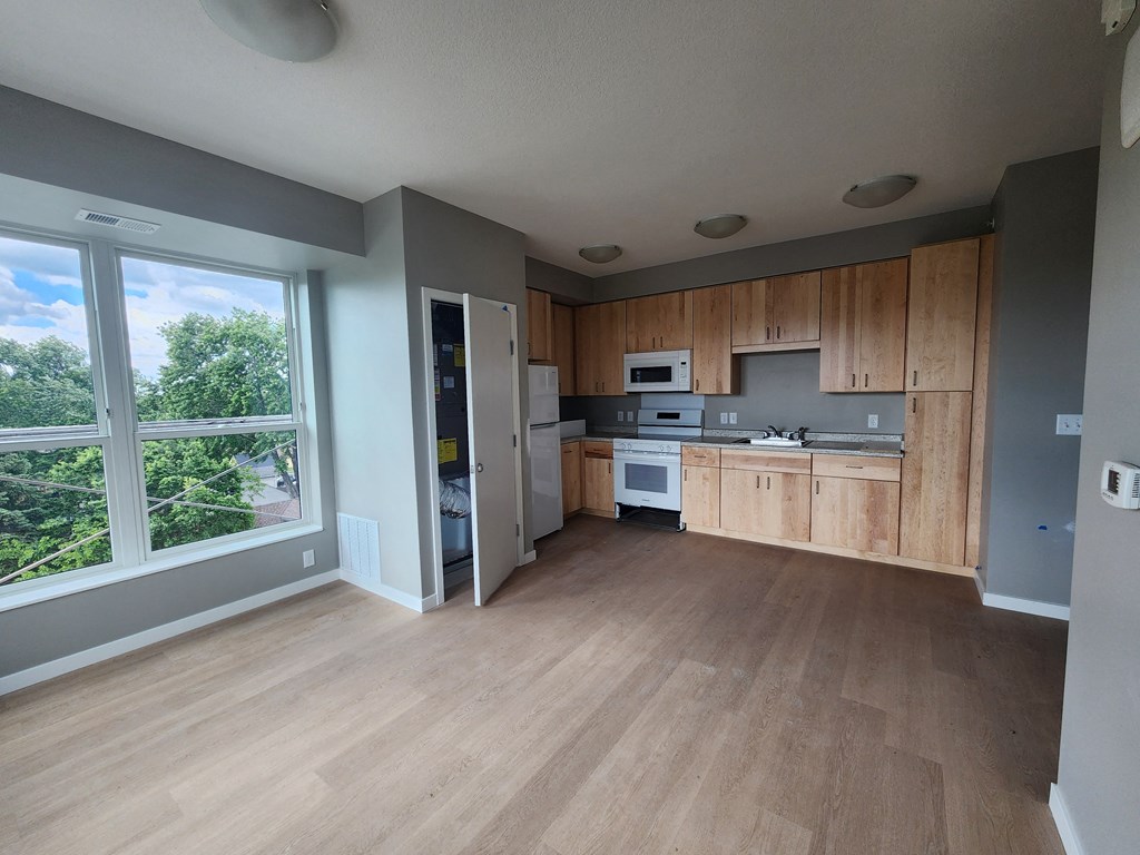an empty kitchen with wooden cabinets and a large window