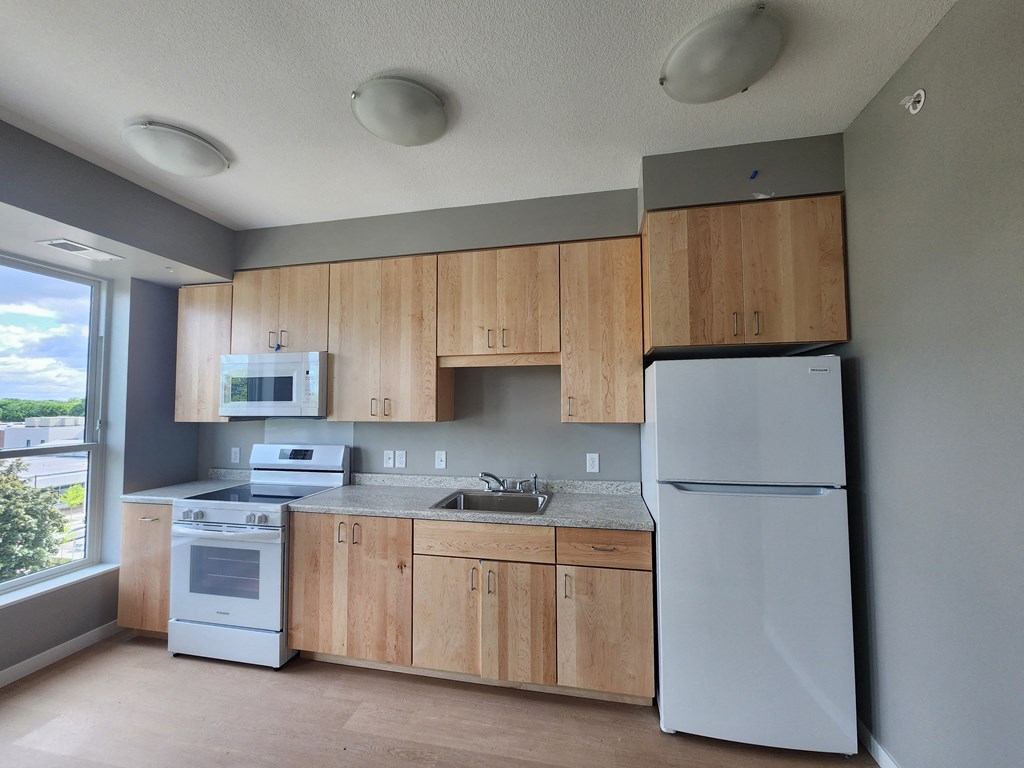 an empty kitchen with white appliances and wooden cabinets
