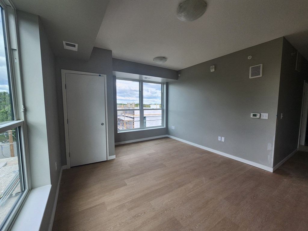 an empty living room with wood floors and a window
