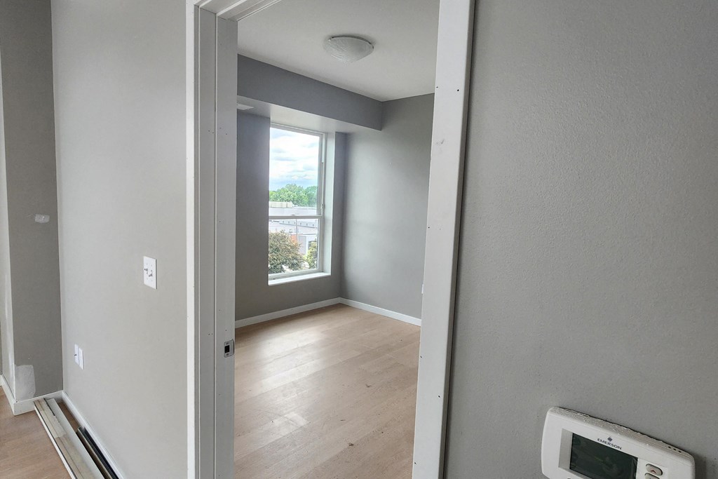 an empty room with a window and wood flooring