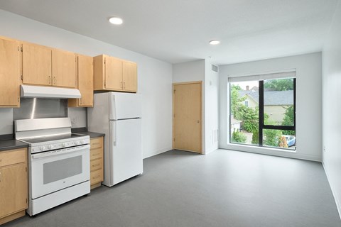 a kitchen with white appliances and wooden cabinets and a window