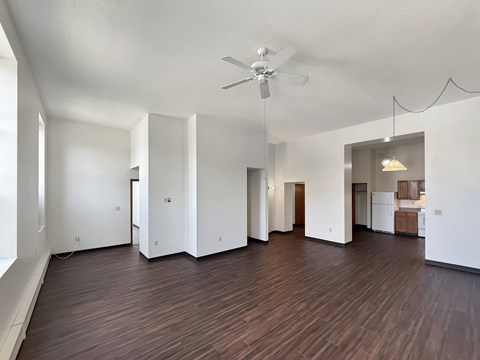 A spacious room with wooden flooring and a ceiling fan.