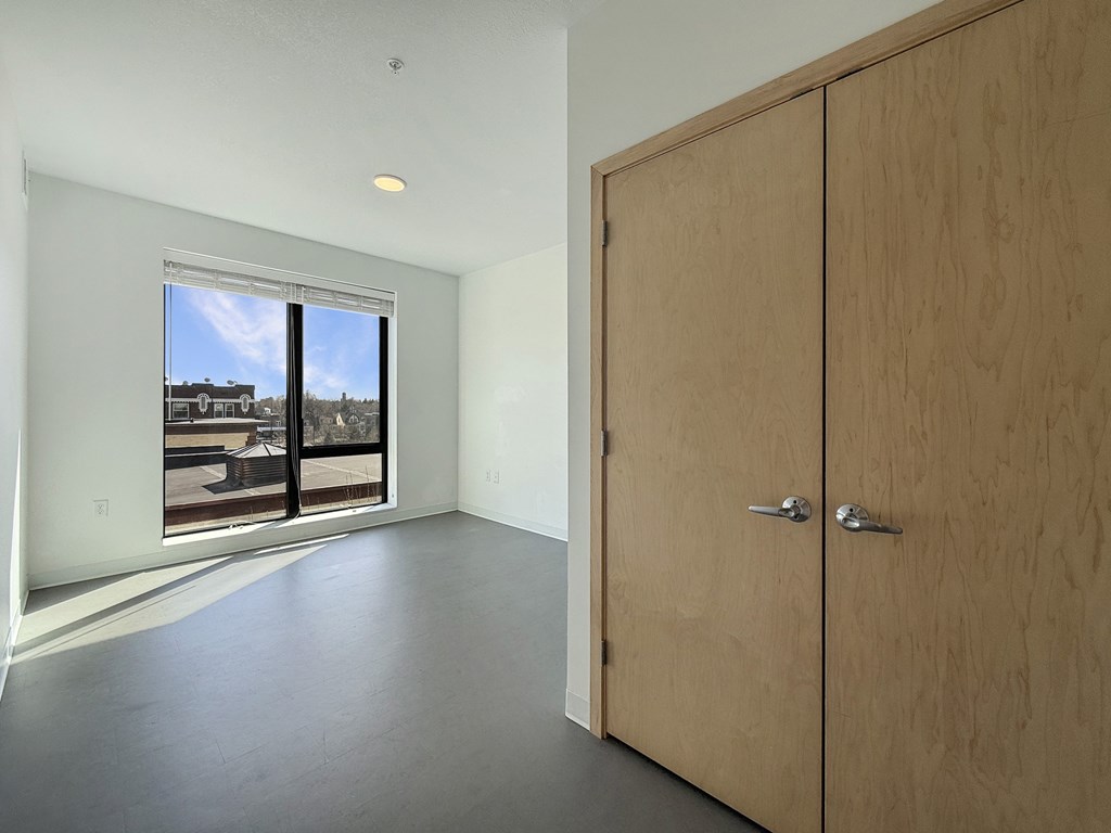 A room with a wooden door and a window overlooking a parking lot.