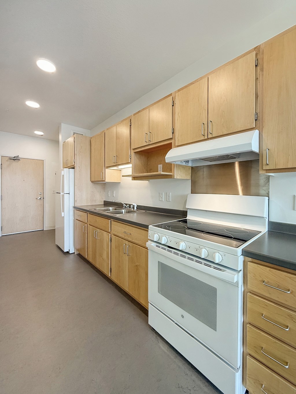 A kitchen with wooden cabinets and a white stove top oven.