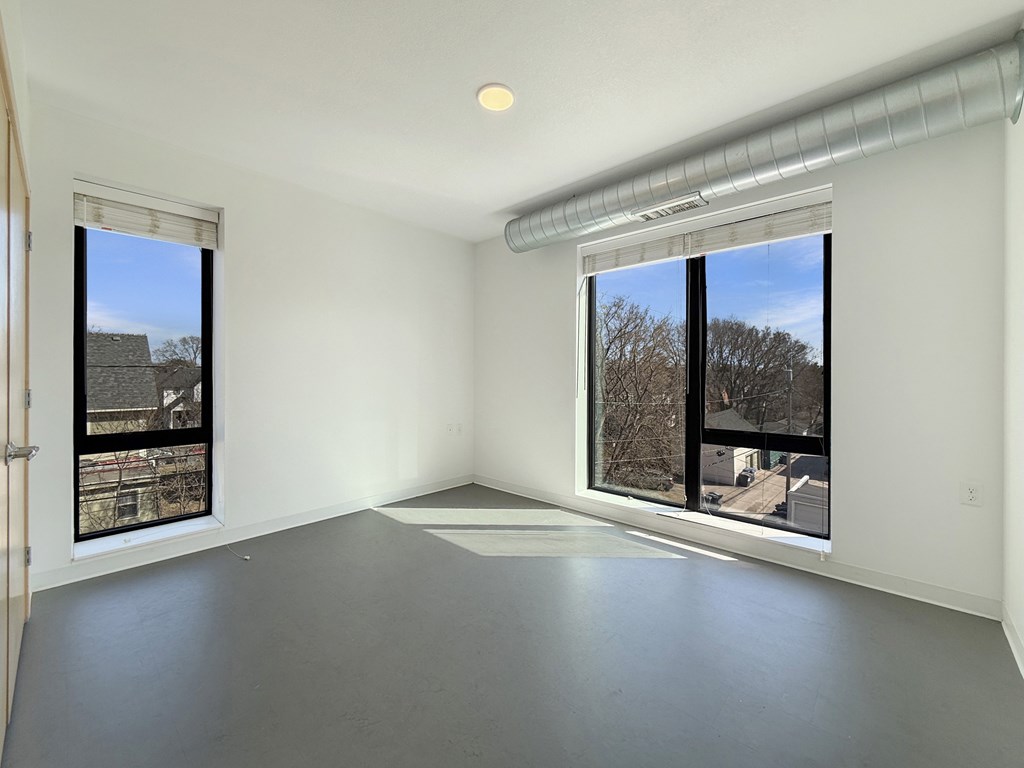 A large empty room with a window overlooking a residential area.