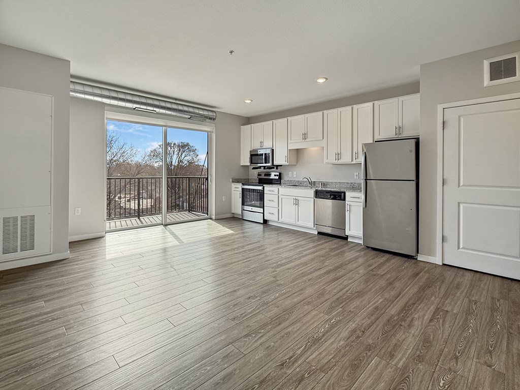 A kitchen with white cabinets and a wooden floor.