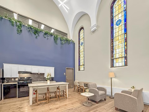 A kitchen with a table and chairs in front of a stained glass window.