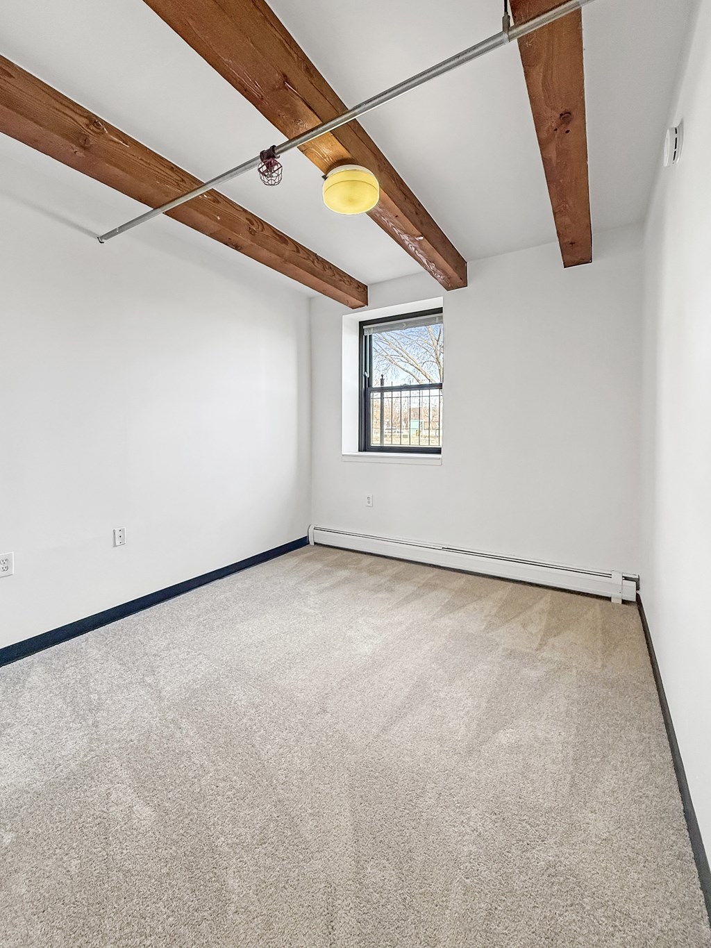 A room with a window and a carpeted floor.