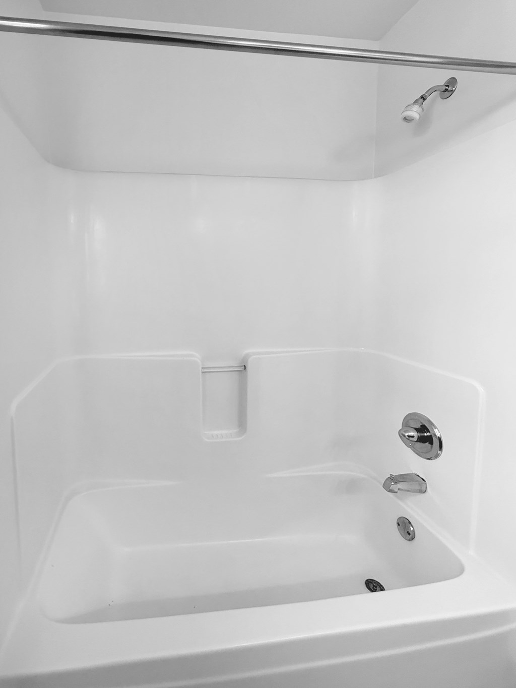 A white bathtub with a shower head above it.