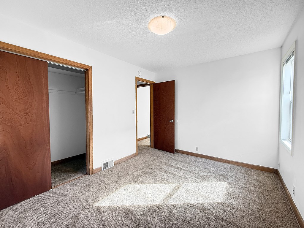 A room with a carpeted floor and two doors.