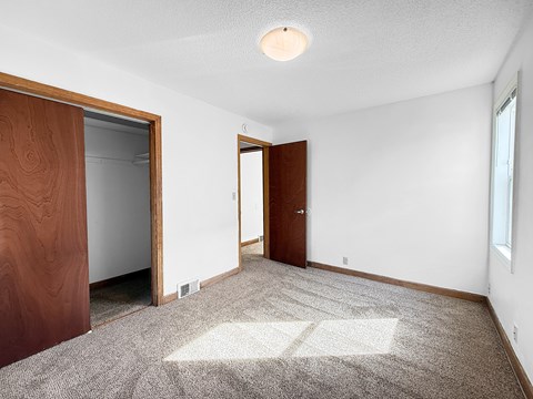 A room with a carpeted floor and two doors.