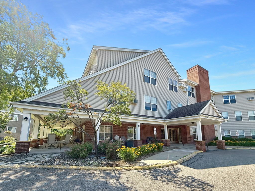 A two-story building with a covered porch and a brick chimney.