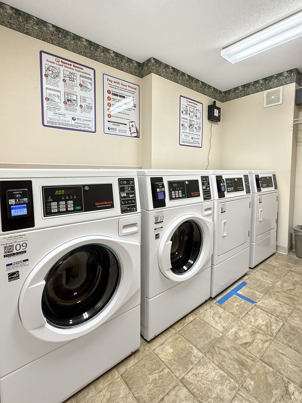 A row of front loading washing machines in a public laundromat.