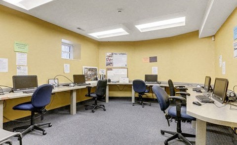 A yellow office space with multiple desks and computers.