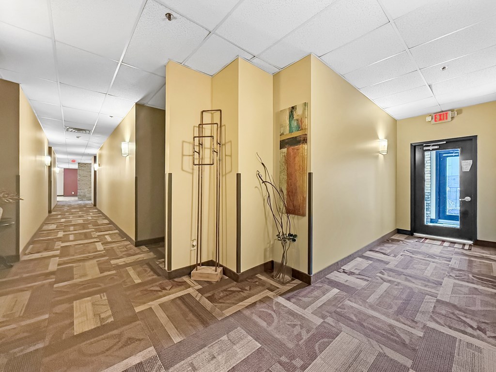 A hallway with tan walls and a carpeted floor.